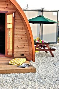 a wooden shelter with an umbrella and a table at Teach Greannai Accommodation Pod in Ross Port
