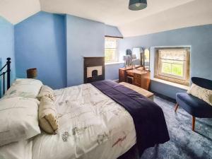 a bedroom with blue walls and a bed and a chair at Rock Cottage in Brassington