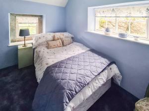 a bedroom with a bed and two windows at Rock Cottage in Brassington