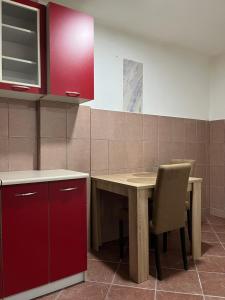 a kitchen with a wooden table and red cabinets at NS apartman in Berane