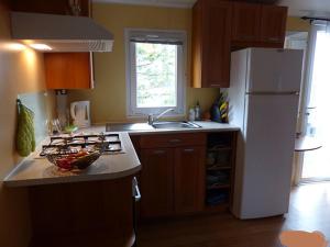 a kitchen with a white refrigerator and a sink at mobil home au Cap Ferret, situé au camping 4 étoiles Siblu les Embruns à Claouey in Lège-Cap-Ferret