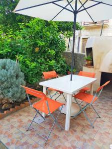 a white table with orange chairs and an umbrella at Casa Vacanze "Il Giardino" in Furnari