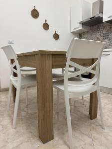 a kitchen with a wooden table and two white chairs at Casa Vacanze Chi mi cunti in Noto +8 photos