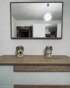 a mirror on a wall with two vases on a shelf at Casa Vacanze Chi mi cunti in Noto