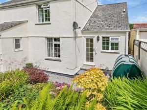 a white house with a green boat in the yard at 1 Bed in Perranporth COLMA in Perranporth