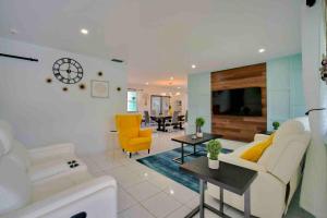 a living room with a white couch and yellow chairs at Villa Las Olas Designed with you in mind! in Fort Lauderdale