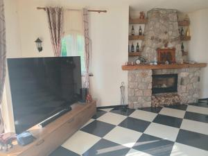 a living room with a large television and a fireplace at Shtepia e Bardhe in Grykë-Orosh