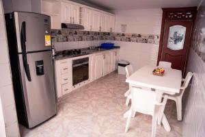 a kitchen with a refrigerator and a table with chairs at Casa Marina Espectacular Casa Completa Valledupar in Valledupar