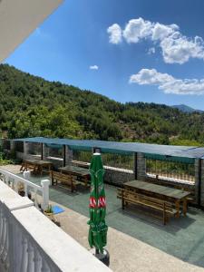 a deck with benches and picnic tables with a mountain at Shtepia e Bardhe in Grykë-Orosh