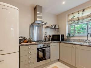 una cucina con mobili bianchi e un forno a piano cottura di 3 Bed in Matlock 90663 a Matlock Altre 15 foto
