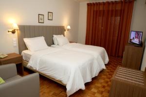 ein Schlafzimmer mit einem großen weißen Bett und einem Fernseher in der Unterkunft Hotel Ribadouro in Alijó + 37 Fotos