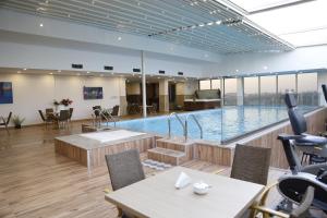 a large swimming pool in a building with a table and chairs at Erbil Quartz Hotel in Erbil