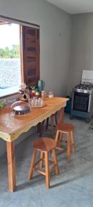 a kitchen with a wooden table and two stools at Chalé sol de Macapá 1- Sua Casa pertinho do Mar in Luis Correia