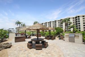 a patio with a table and a umbrella and benches at Luxurious 2BR Gulfview Condo On Siesta Key Steps To The Beach Gulf Horizon in Sarasota