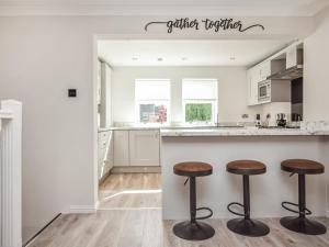 a white kitchen with two stools at a counter at The White House in Callander