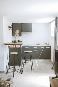 une cuisine avec une table et deux tabourets dans l'établissement Carignan - Gîtes Du Mas Des Jeux, à Saint-Laurent-dʼAigouze