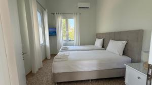 a bedroom with two beds and a window at Magdalini Garden House in Paralion astros