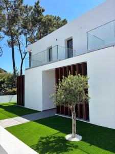 a white house with a tree in the yard at Aroeira Beach Home in Almada