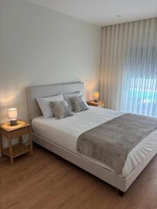 a bedroom with a large bed with two lamps on tables at Aroeira Beach Home in Almada +11 photos