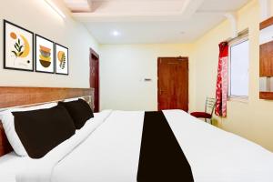 1 dormitorio con 1 cama blanca grande con almohadas negras en Super Townhouse Sankaramatam Road Near Diamond Park, en Visakhapatnam