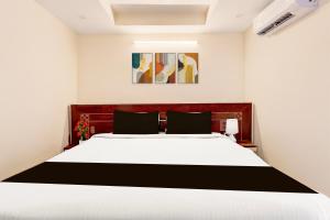 1 dormitorio con 1 cama blanca grande con almohadas negras en Super Townhouse Sankaramatam Road Near Diamond Park, en Visakhapatnam 21 fotos más