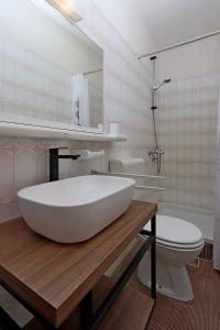 a bathroom with a large white sink and a toilet at Apartments by the sea Supetarska Draga - Donja, Rab - 5030 in Supetarska Draga