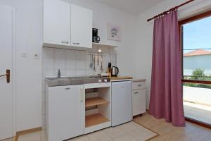 a kitchen with white cabinets and a sink and a window at Apartments by the sea Supetarska Draga - Donja, Rab - 5030 in Supetarska Draga +29 photos