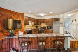 una cocina con armarios de madera y una gran isla con sillas de bar en Powder Ridge 108 Apartment, en Breckenridge