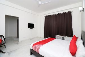a bedroom with a bed with red pillows and a television at Hotel O The Primero Near Leisure Valley Park in Gurgaon