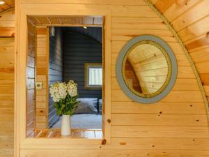 Un espejo en la pared de una cabaña con un jarrón de flores. en 1 Bed in Coniston 88961, en Coniston