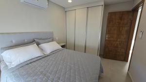 a bedroom with a bed with white sheets and a wooden door at Departamento a estrenar en Mburucuya in Asuncion