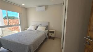 a bedroom with a white bed and a window at Departamento a estrenar en Mburucuya in Asuncion
