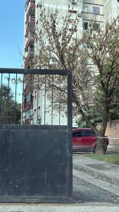 a red car is parked next to a fence at Departamento luminoso Bulnes 3 dormitorios in San Miguel de Tucumán +8 photos