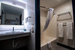 a bathroom with a sink and a mirror and a tub at SureStay by Best Western Forsyth in Forsyth