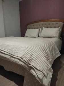 un letto con piumone e cuscini bianchi di Cantinho do aconchego a Campos do Jordão