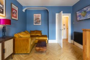een woonkamer met een bank en blauwe muren bij Centre Meadowside Residence in Edinburgh