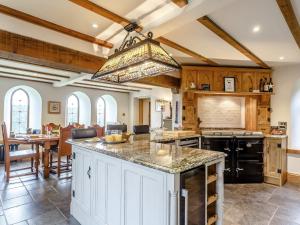 a kitchen with a large island with a chandelier at 4 Bed in Latchley 77480 in Sydenham Damerel