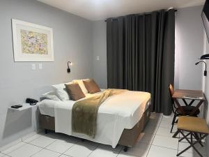 a bedroom with a bed and a table and a chair at Hotel Concord e Eventos corporativos Campo Grande in Campo Grande