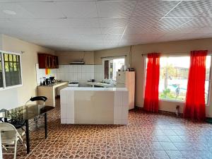 una cucina con tende rosse e un tavolo e una cucina con di Isabella Hostel and Pool ad Alto Boquete
