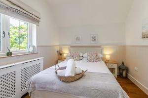 a white bedroom with a bed with a basket on it at Stable Cottage in Ringwood