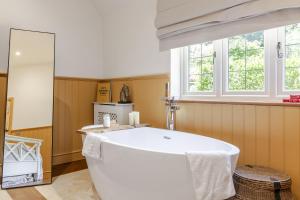 a white bath tub in a bathroom with a window at Stable Cottage in Ringwood