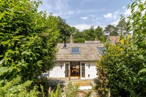 a white house with trees in front of it at Stable Cottage in Ringwood