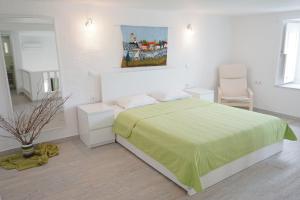 een witte slaapkamer met een bed met een groene deken bij Kiki's Houses Vlichos in Hydra