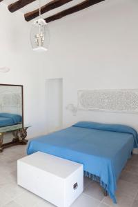 a white bedroom with a blue bed and a mirror at Note di Salina in Santa Marina Salina