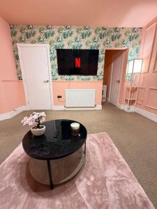 a living room with a table and a tv at The Rosy Retreat By Station in Cambridge