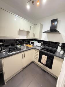 a kitchen with white cabinets and a stove top oven at The Rosy Retreat By Station in Cambridge +19 photos