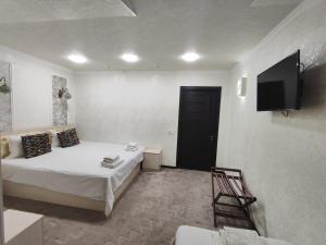 een slaapkamer met een bed en een flatscreen-tv bij Hotel Suzani Samarkand in Samarkand