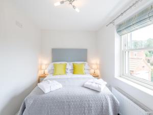 a white bedroom with a bed with yellow pillows at 5 Bed in Tealby 78678 in Tealby