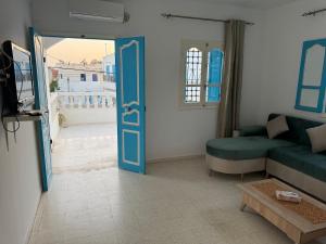 a living room with a blue door and a couch at Dar El Fell - Étage de Villa à Djerba Houmt Souk in Houmt Souk