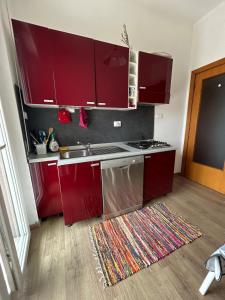 a kitchen with red cabinets and a sink and a rug at Arya in Montesilvano